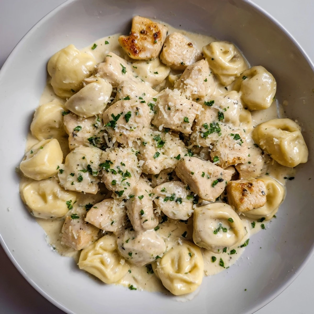 Zesty Cajun Garlic Parmesan Chicken Tortellini: creamy pasta dish with tender chicken, red bell peppers, and fresh parsley.