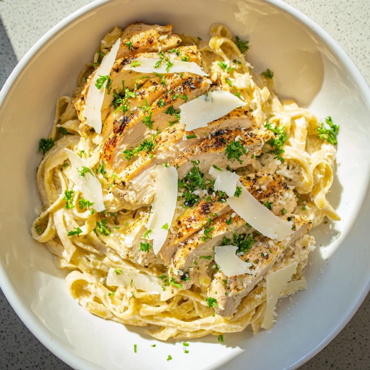 Plate of Spicy Cajun Chicken Alfredo, creamy sauce coating fettuccine, topped with sliced chicken.