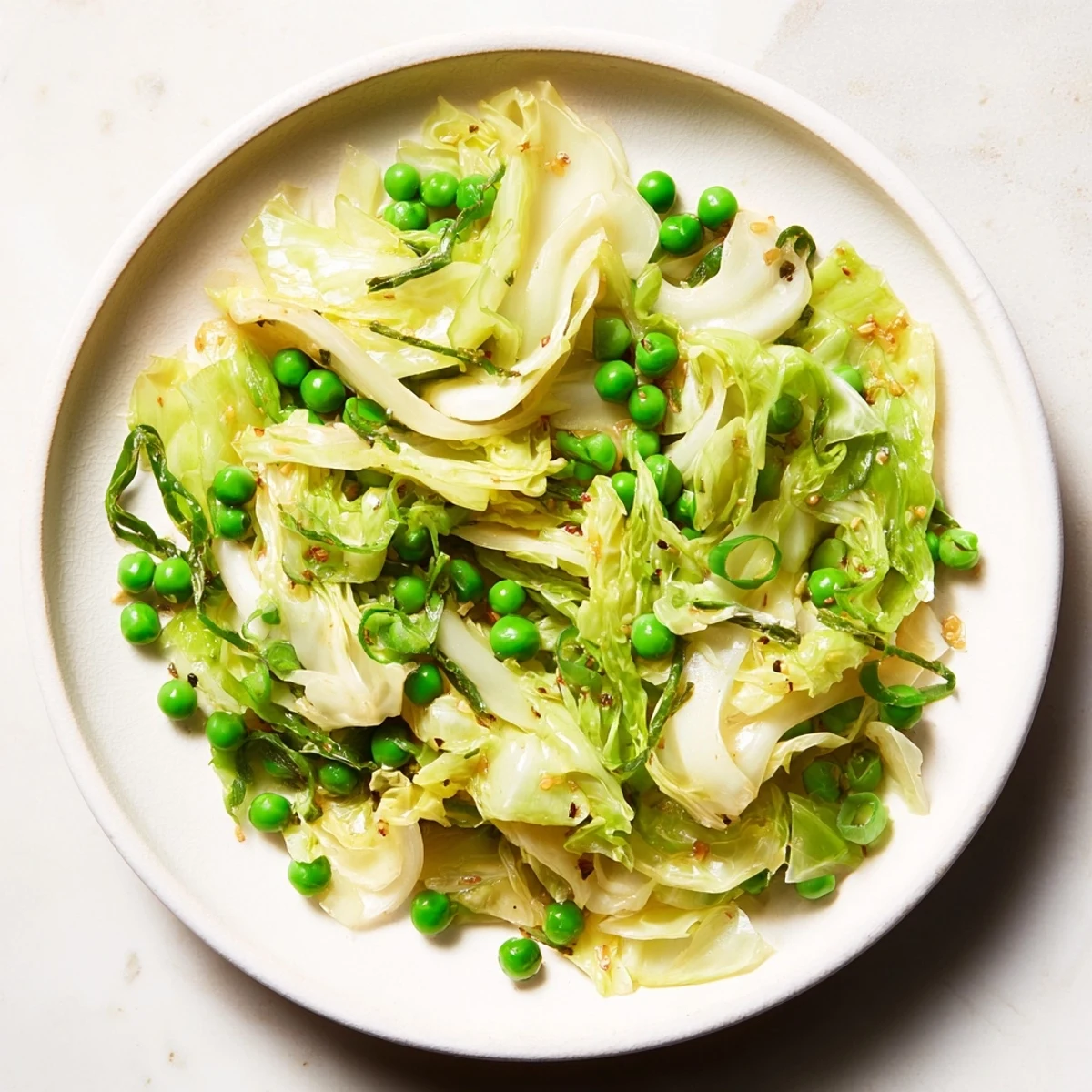 Steaming cabbage stir-fry with garlic, soy, and peas, ready to serve as a vegetarian side dish.
