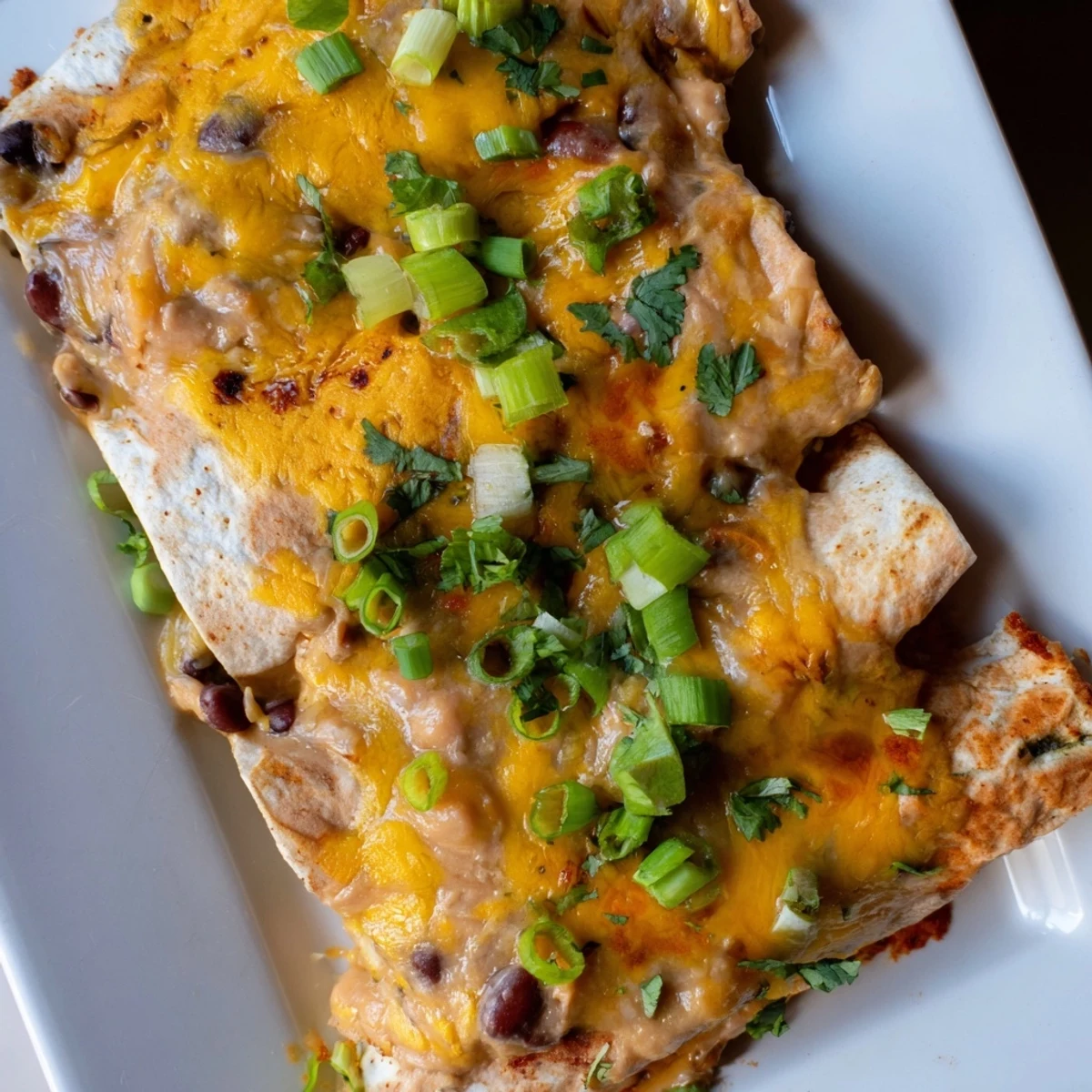 Steaming Cheesy Bean Enchiladas with bubbly, golden cheese, a homemade Mexican-cuisine comfort food.