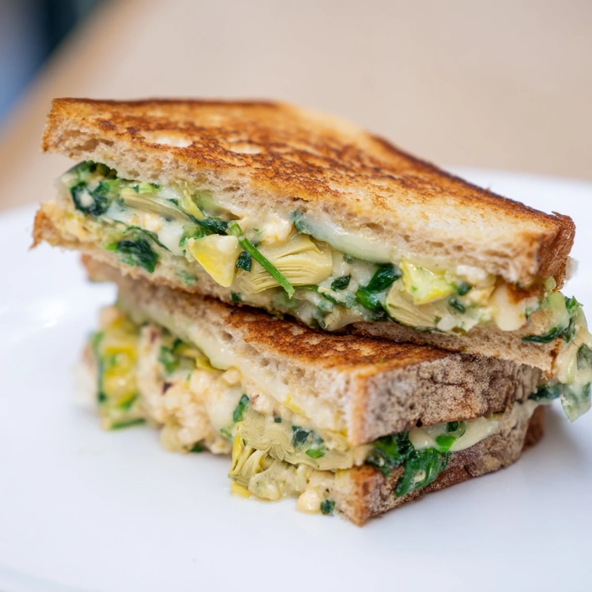Toasty sourdough bread encases creamy Sourdough Spinach Artichoke Dip Grilled Cheese; a hearty vegetarian meal.