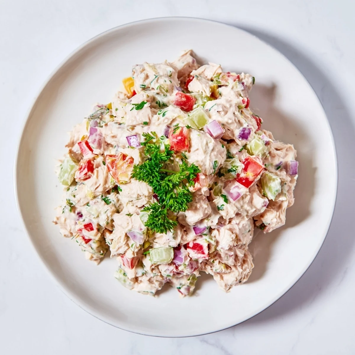 Creamy canned chicken salad with vibrant red peppers served on a bed of lettuce.