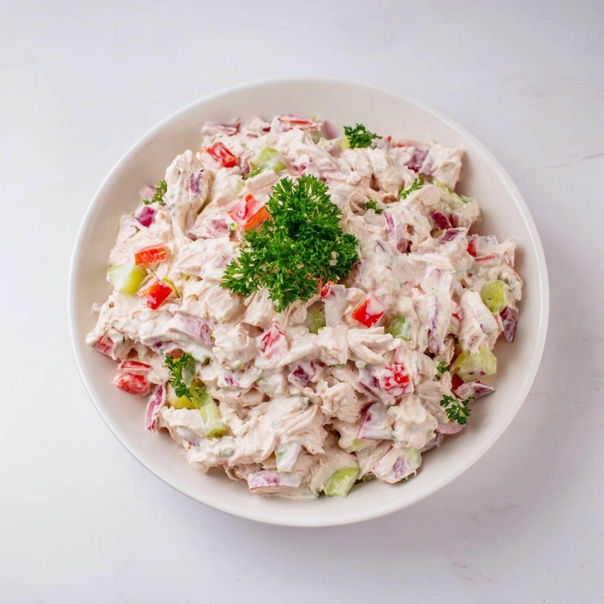 A close-up of delicious canned chicken salad speckled with herbs, ready to serve.