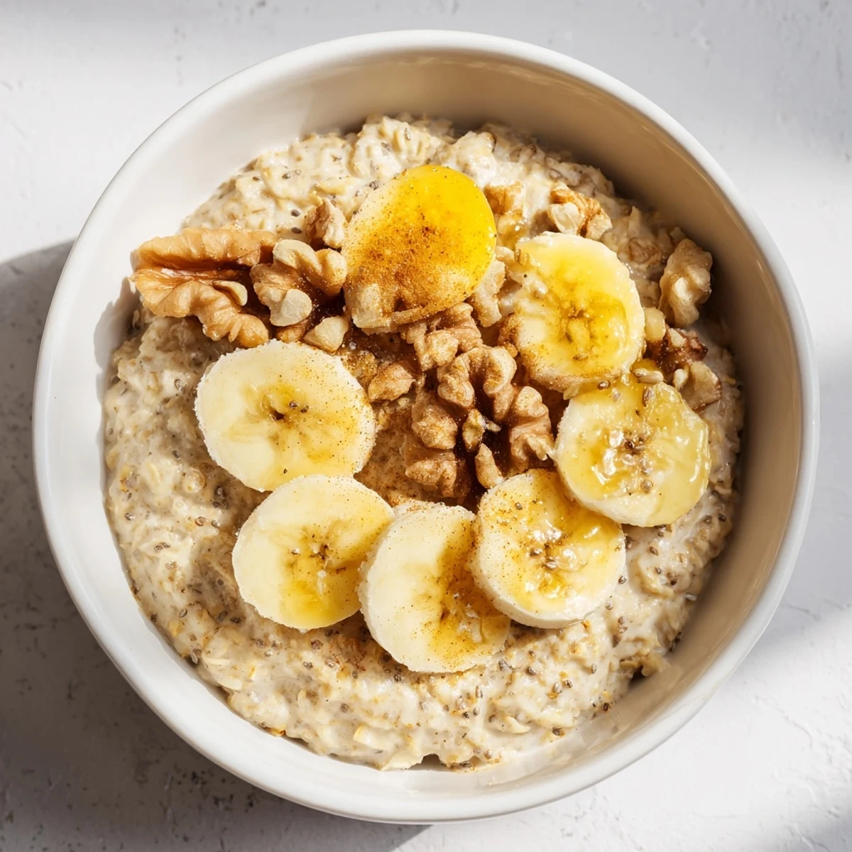 Warm, creamy Microwave Banana Oats topped with fresh banana and crunchy walnuts for breakfast.