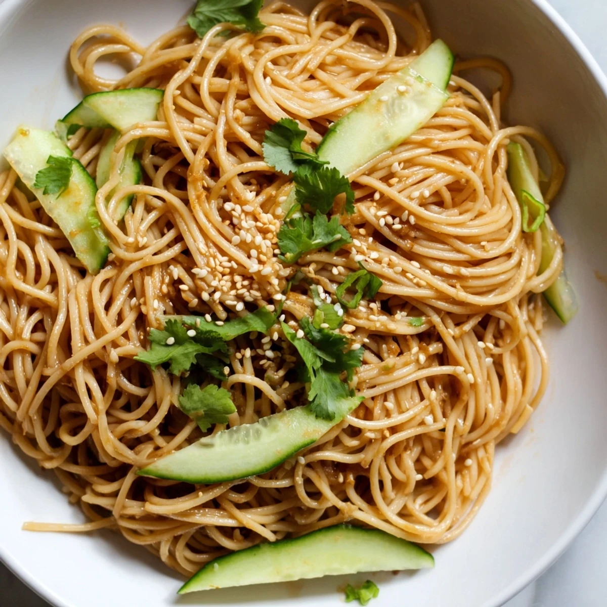 Chilled Spicy Sesame Noodle Salad tossed with crisp cucumber slices and fresh cilantro, served ready to eat.