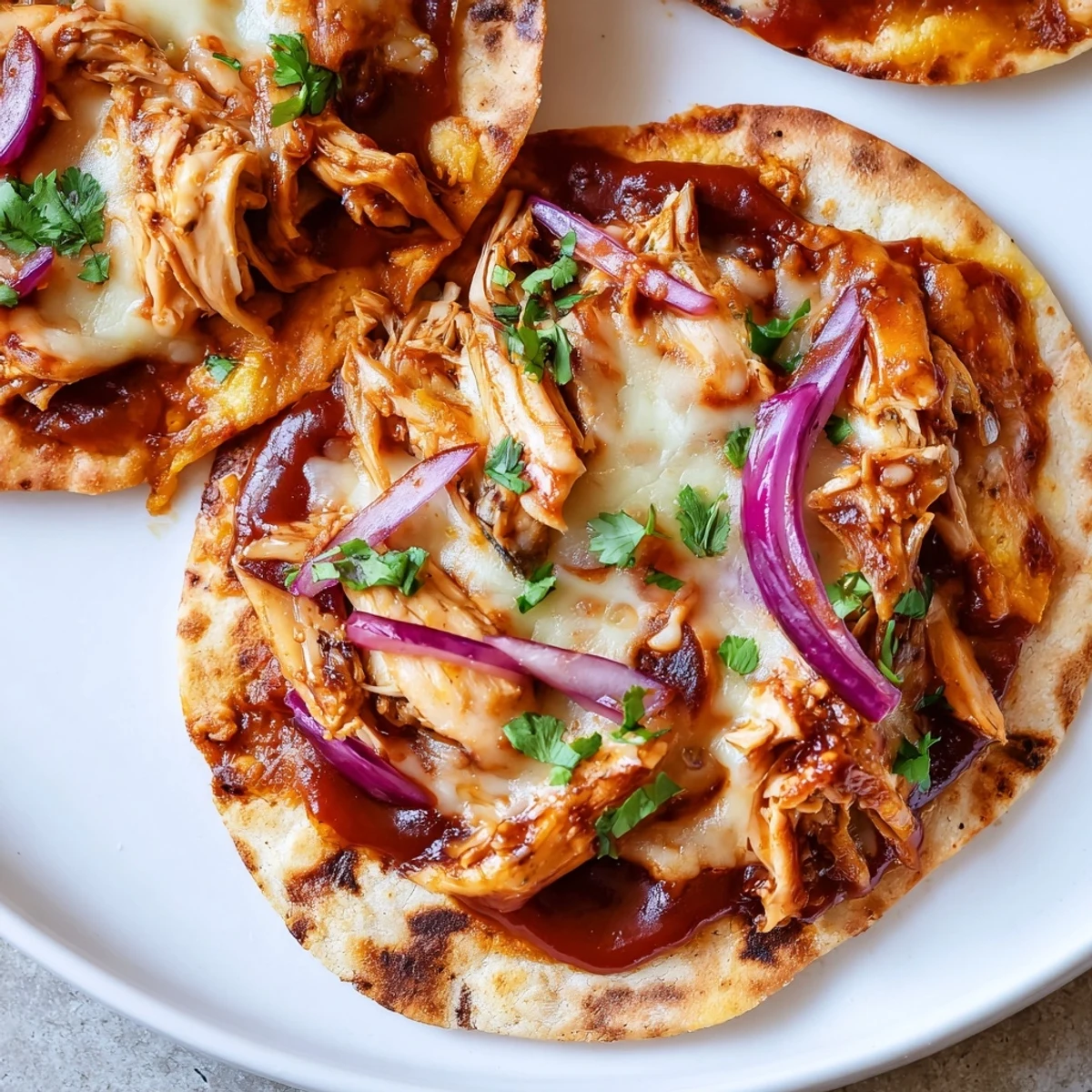 A sliced wedge of BBQ Chicken Flatbread reveals stacked layers of tender chicken and sweet onions on a rustic cutting board.
