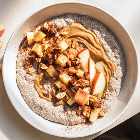 Creamy Apple-Chia Pudding with peanut butter swirls, fresh apple chunks, and sprinkled peanuts in a glass.