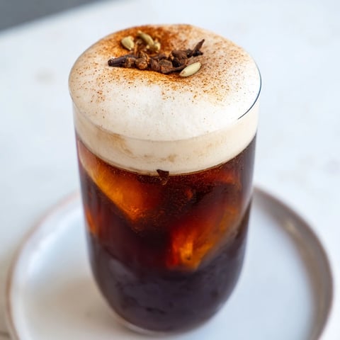 Frothy cold foam swirls atop a refreshing homemade iced chai, perfect for a summer treat.