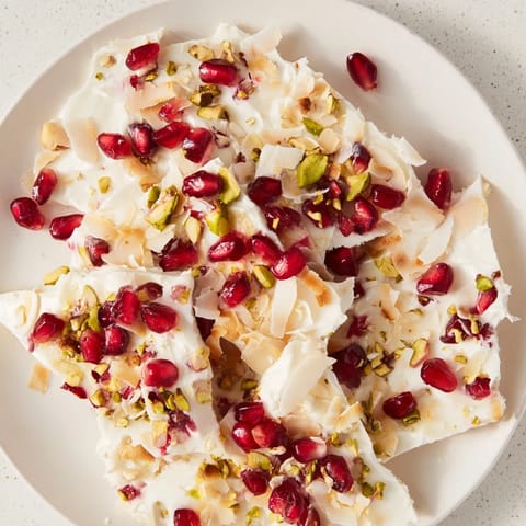 Homemade Frozen Yogurt Bark topped with glistening pomegranate seeds and chopped pistachios, ready to serve.