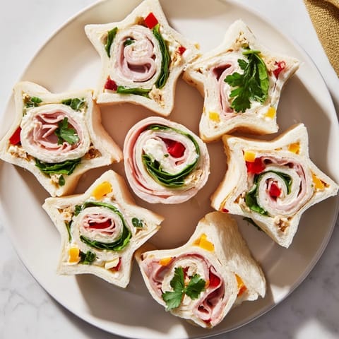 Delicious, festive party sandwiches, showing colorful ham, turkey, and cheese roll-ups arranged.