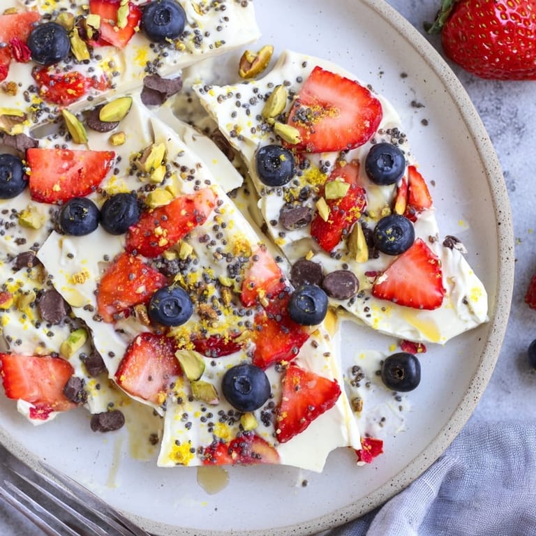 Greek yogurt frozen bark, topped with glistening berries and chopped pistachios for a cool treat.