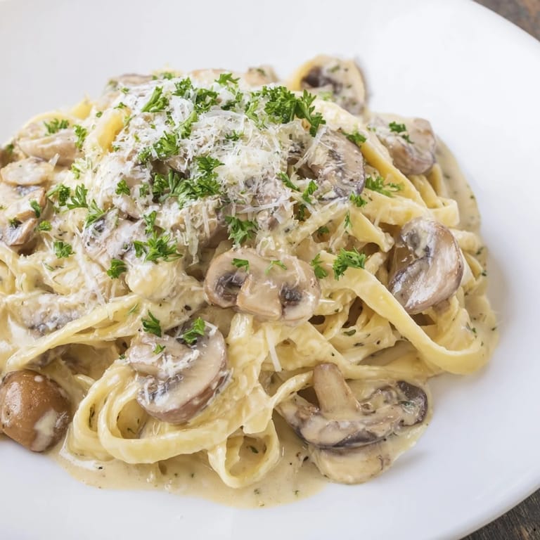 Serving suggestion for creamy mushroom Alfredo pasta, ready to enjoy with a sprinkle of parmesan and a glass of white wine.